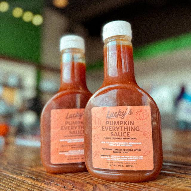 Two bottles of Lucky's Pumpkin Everything Sauce on a wooden surface with a blurred background.